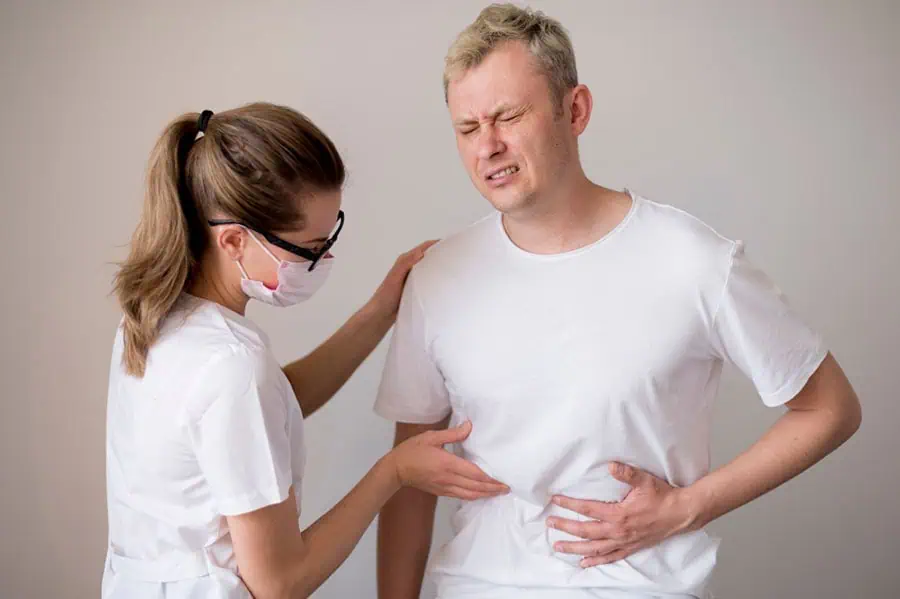 Doctor examining a man with abdominal pain, a common symptom of Chronic Kidney Disease.