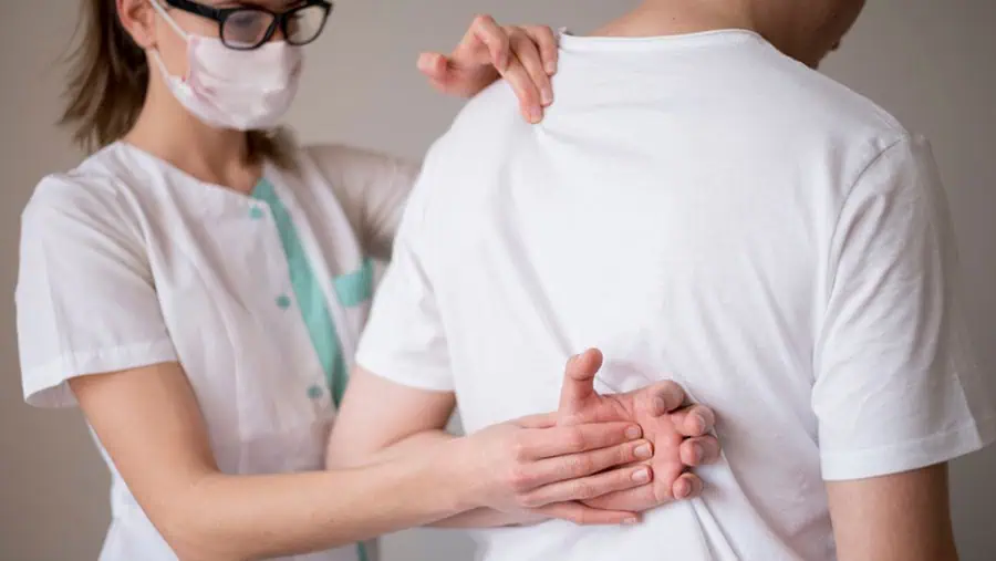 Doctor examining a patient with lower back pain, a potential symptom of Chronic Kidney Disease.